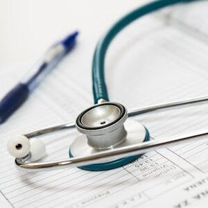 Stetoskop i olovka naslonjeni na medicinski izveštaj u zdravstvenoj ustanovi.