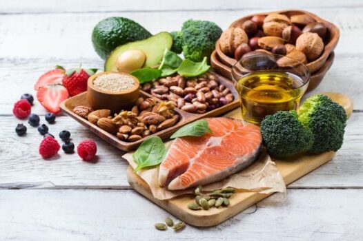 Izbor zdrave hrane riba, povrće, voće maslinovo ulje, orašasti plodovi na belom rustičnom drvenom stolu.