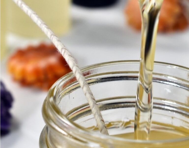 Mlaz ulja koji se sliva u teglu koja se nalazi na stolu, u krupnom planu